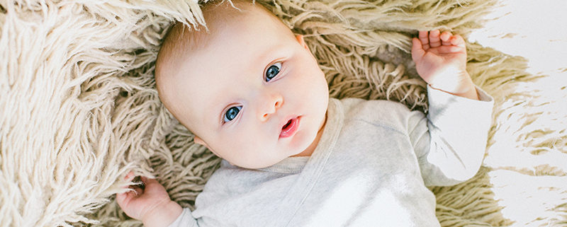 photo of a cute infant on a furry white rug, illustrating baby brain development