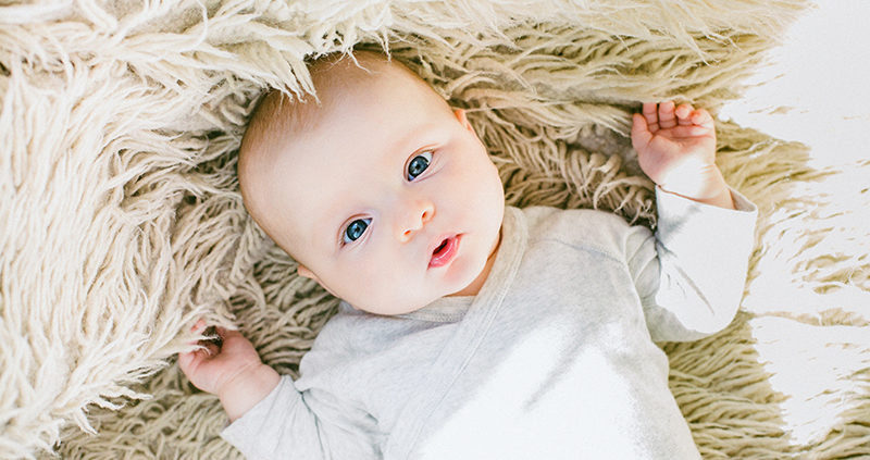 photo of a cute infant on a furry white rug, illustrating baby brain development