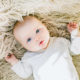 photo of a cute infant on a furry white rug, illustrating baby brain development