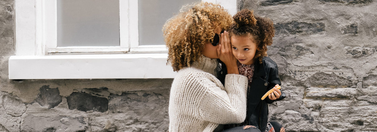 How to Talk to Kids: Image of a mother whispering in her daughter's ear