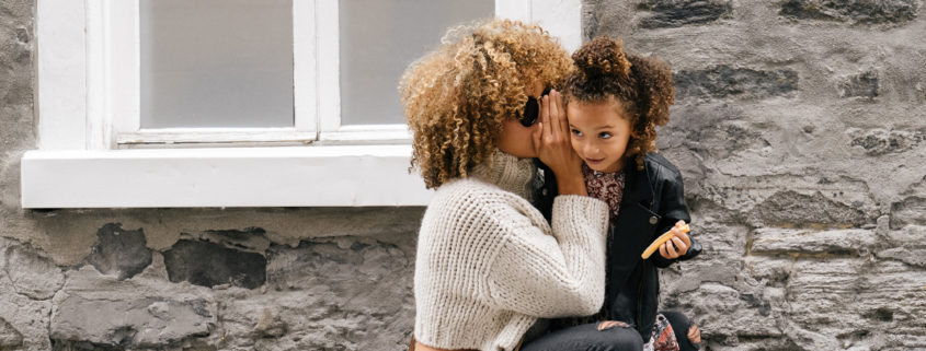 How to Talk to Kids: Image of a mother whispering in her daughter's ear